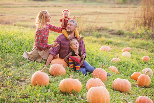 Famille heureuse avec des citrouilles orange dans le champ d'automne