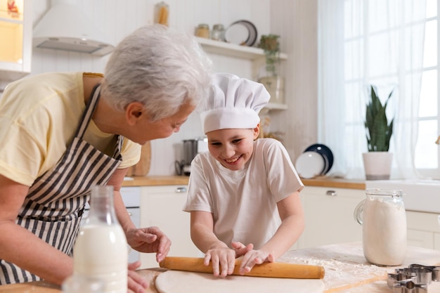 Famille heureuse dans la cuisine grand-mère et petite-fille enfant cuisinier dans la cuisine ensemble grand-mère enseignant