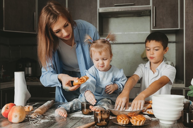 Famille heureuse dans la cuisine. maman et les enfants préparent la pâte et font une tarte pour la fête des mères.