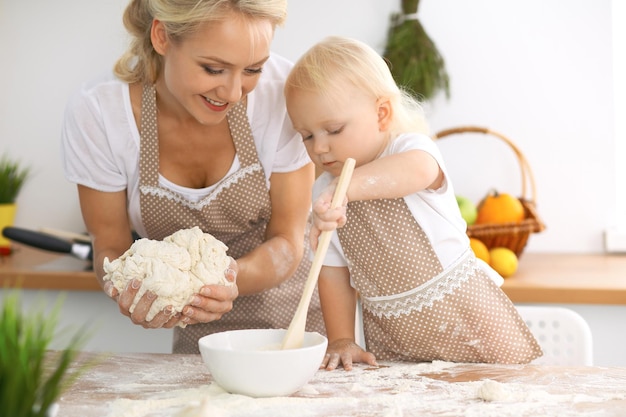 Famille heureuse dans la cuisine. Mère et enfant fille cuisinant une tarte ou des biscuits de vacances pour la fête des mères, série de photos de style de vie décontracté dans l'intérieur de la vie réelle