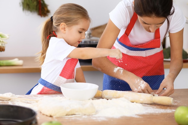 Photo famille heureuse dans la cuisine mère et enfant fille cuisinant une tarte ou des biscuits de vacances pour la fête des mères