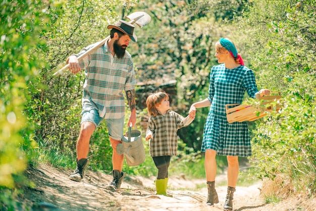 Famille heureuse dans les fermes de jardin couple avec fils profiter de la nature printanière et prendre soin de ses plantes fa