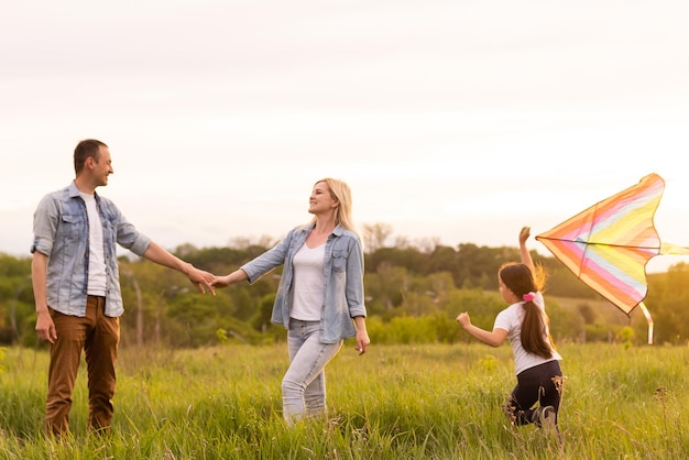 Famille heureuse dans la lumière du soir du parc. Les lumières d'un soleil. Maman, papa et bébé se promènent au coucher du soleil. Le concept d'une famille heureuse.