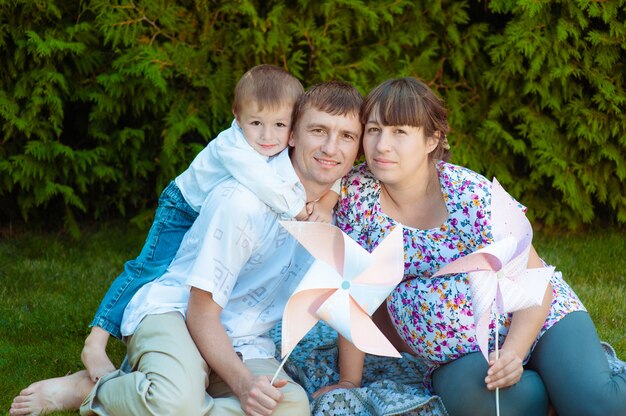 Famille heureuse dans le parc. Heureuse maman, papa et bébé est assis sur l'herbe. Le concept d'une famille heureuse.