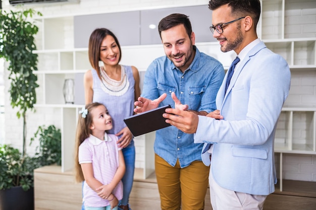 Famille heureuse discutant avec un agent immobilier de l'achat d'une nouvelle maison.