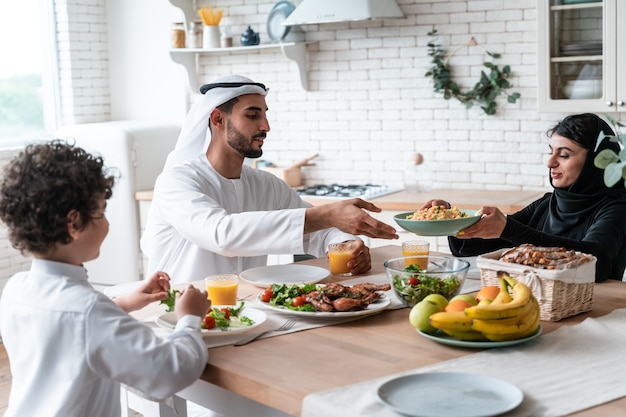 Famille heureuse des émirats arabes unis mangeant ensemble et célébrant les vacances de la fête nationale