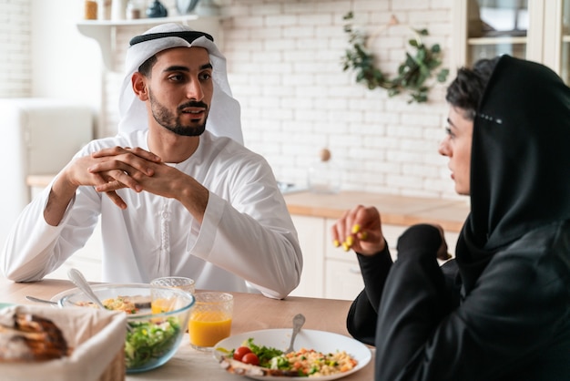 Famille heureuse des émirats arabes unis mangeant ensemble et célébrant les vacances de la fête nationale