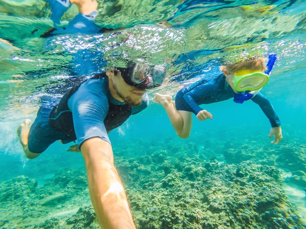 Famille heureuse enfant actif en masque de plongée sous-marine plongée sous-marine voir des poissons tropicaux dans la piscine de mer de récif de corail Voyage aventure activité de natation sur les vacances d'été à la plage avec enfant
