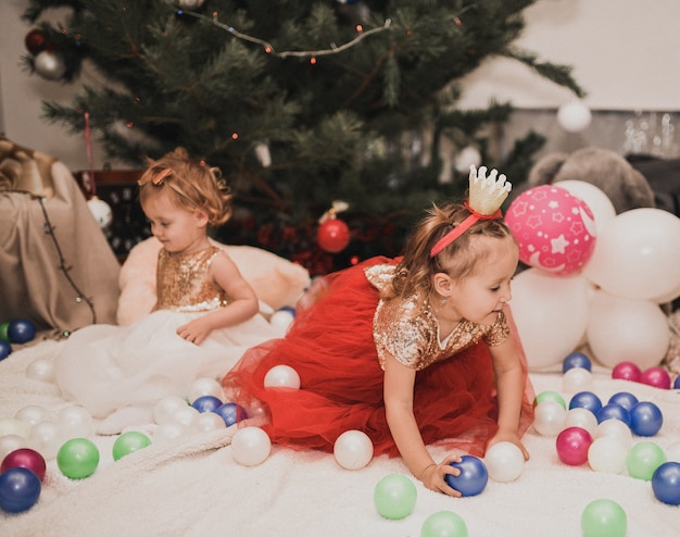 Famille heureuse avec enfant célébrant le Nouvel An et Noël à l'arbre de Noël décoré et aux guirlandes