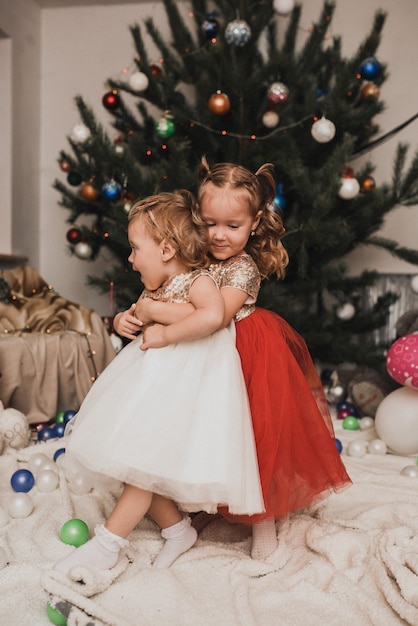 Famille heureuse avec enfant célébrant le Nouvel An et Noël à l'arbre de Noël décoré et aux guirlandes