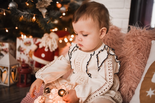 Famille heureuse avec enfant célébrant le Nouvel An et Noël à l'arbre de Noël décoré et aux guirlandes