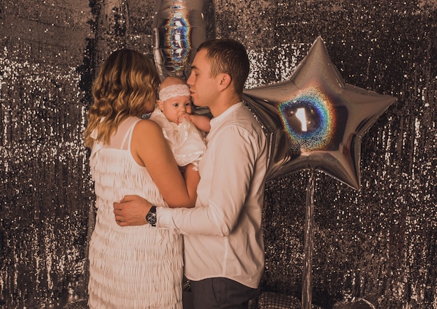 Famille heureuse avec enfant célébrant le Nouvel An et Noël à l'arbre de Noël décoré et aux guirlandes