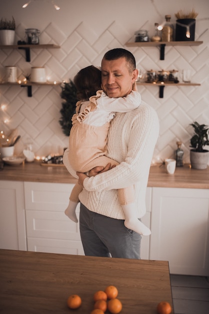 Famille heureuse avec enfant célébrant le Nouvel An et Noël à l'arbre de Noël décoré et aux guirlandes