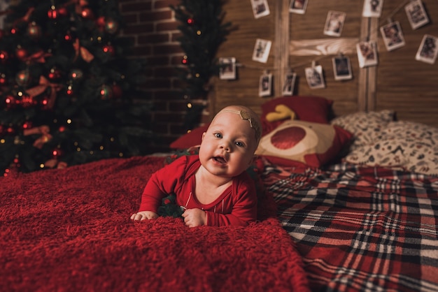 Famille heureuse avec enfant célébrant le Nouvel An et Noël à l'arbre de Noël décoré et aux guirlandes