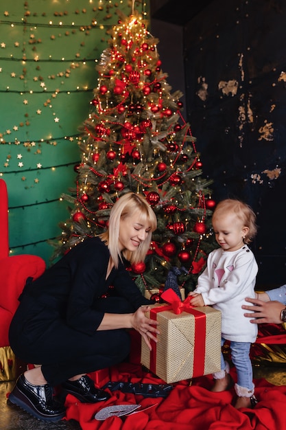 Une famille heureuse avec un enfant fête le nouvel an près de l&#39;arbre de Noël