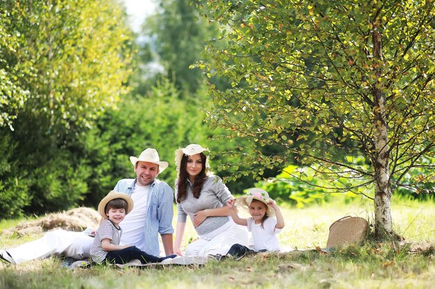 Famille heureuse avec des enfants ayant un pique-nique dans le parc parents avec des enfants assis sur l'herbe du jardin et mangeant de la pastèque à l'extérieur