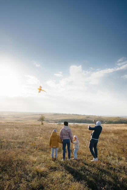 Une famille heureuse avec des enfants lance un cerf-volant et passe du temps ensemble au grand air. Bonne enfance et vacances en famille.