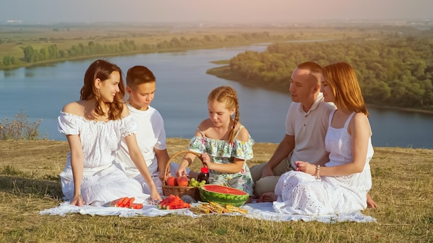 Famille heureuse avec enfants a pique-nique sur la rive vallonnée