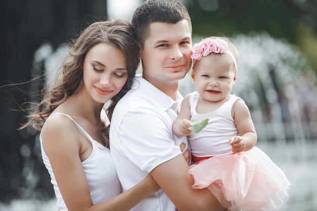 Famille heureuse à l'extérieur. Parents marchant dans le parc avec leur petit bébé mignon. Jeune famille.