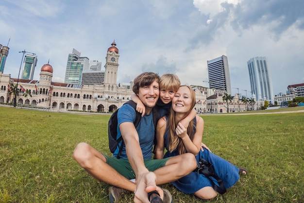 Une famille heureuse fait du selfie sur le fond de la place Merdeka et du bâtiment Sultan Abdul Samad. Voyager avec le concept d'enfants