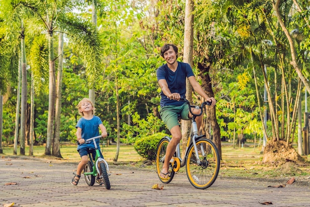 Une famille heureuse fait du vélo à l'extérieur et sourit. Père à vélo et fils à vélo d'équilibre