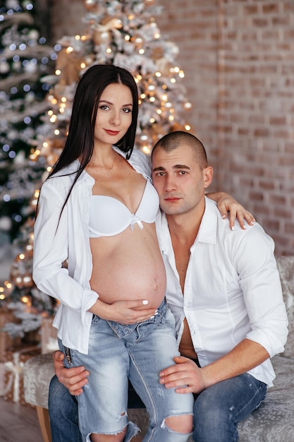 Famille heureuse une femme enceinte et un homme en denim dans la salle blanche programmes hypothécaires et sociaux pour soutenir les jeunes familles vêtements à la mode et confortables pour le bonheur familial de la parentalité