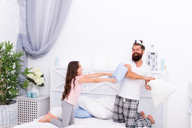 Famille heureuse de fille et papa jouant et se battant avec des oreillers s'amusant ensemble bonheur