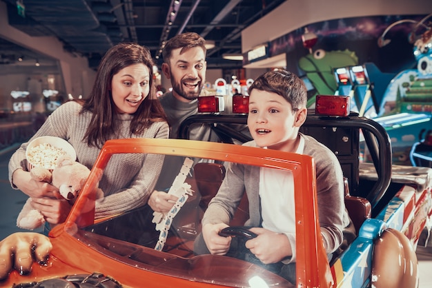 Famille heureuse, fils ravis assis sur une voiture de jouet