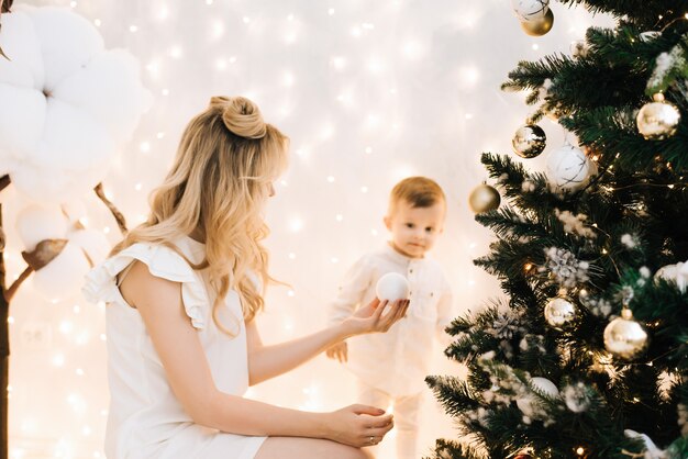 Famille heureuse à l'intérieur de la maison avec arbre de Noël et cadeaux. Belle mère avec son enfant parmi les décorations de Noël.