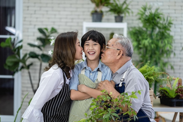 Famille heureuse jardinant ensemble dans le jardin grand-père petit-fils et femme prenant soin de la nature