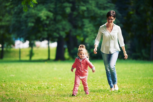 famille heureuse jouant ensemble en plein air dans le parc mère avec enfants courant sur l'herbe