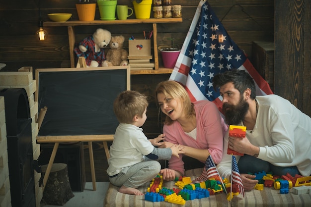 Une famille heureuse joue avec des constructeurs colorés et des drapeaux de jouets