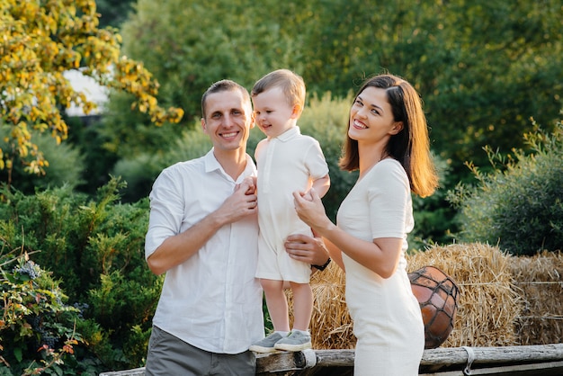 Famille heureuse avec leur fils marchant dans le parc au coucher du soleil. Bonheur. L'amour