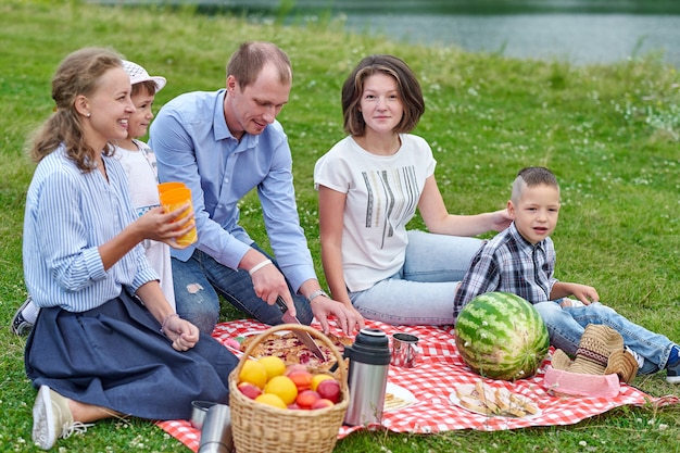 Famille heureuse lors d'un pique-nique. Pique-nique au pré ou au parc. Jeunes amis et leurs enfants dans la nature.