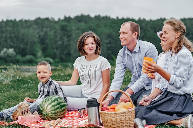 Famille heureuse lors d'un pique-nique. Pique-nique dans la prairie ou le parc. Jeunes amis et leurs enfants dans la nature