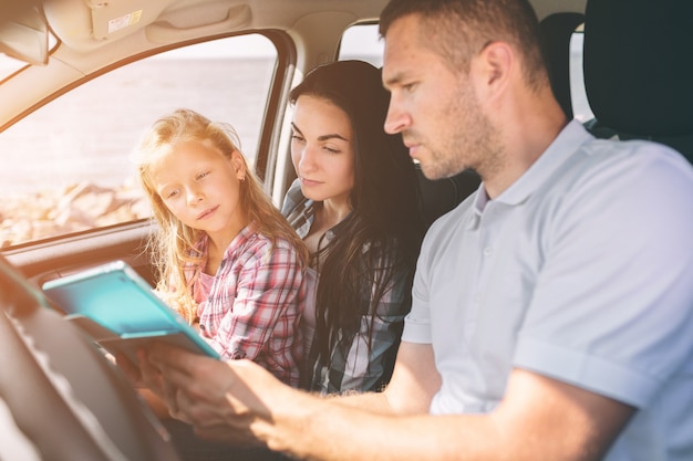 Famille heureuse lors d'un road trip dans leur voiture. Papa, maman et sa fille voyagent au bord de la mer, de l'océan ou de la rivière. Balade d'été en automobile