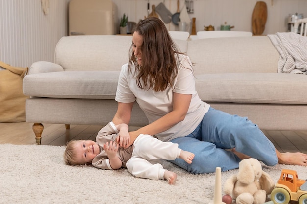 Famille heureuse à la maison mère et bébé garçon jouant avec des jouets à la maison à l'intérieur petit enfant en bas âge et