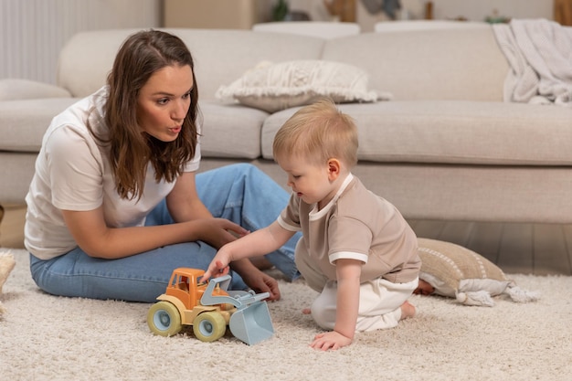 Famille heureuse à la maison mère et bébé garçon jouant avec des jouets à la maison à l'intérieur petit enfant en bas âge et