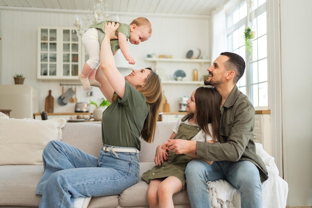 Photo famille heureuse à la maison mère père deux enfants filles se relaxant sur le canapé intérieur maman père parents bébés filles enfants se relaxant jouant s'amusant ensemble famille souriant riant profitant d'un moment tendre