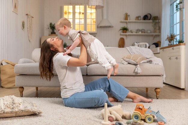 Famille heureuse à la maison mère soulevant dans l'air petit enfant enfant fils maman et bébé garçon jouant ayant