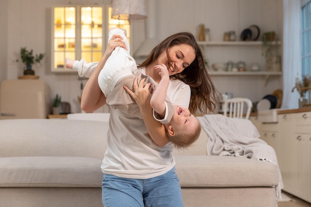 Famille heureuse à la maison mère soulevant dans l'air petit enfant enfant fils maman et bébé garçon jouant ayant