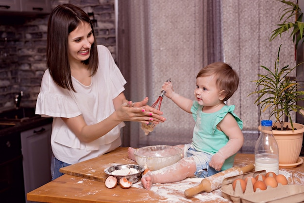 Famille heureuse, maman, fille jouer et cuisiner dans la cuisine, pétrir la pâte et cuire des biscuits
