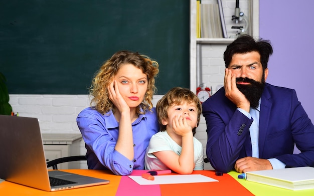 Une famille heureuse, maman et papa, aide un enfant garçon pour la première fois à l'école