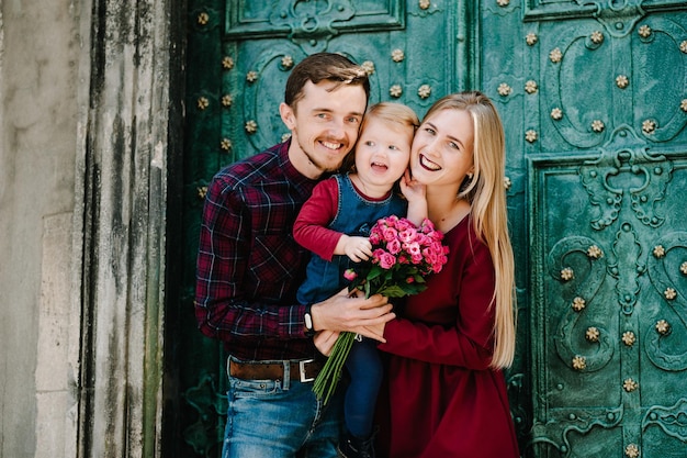 Famille heureuse : maman, papa, fille avec bouquet de fleurs profitant du temps ensemble.