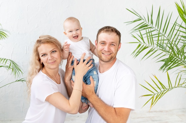 Famille heureuse, maman, papa et fils de bébé souriant sur fond blanc et étreignant