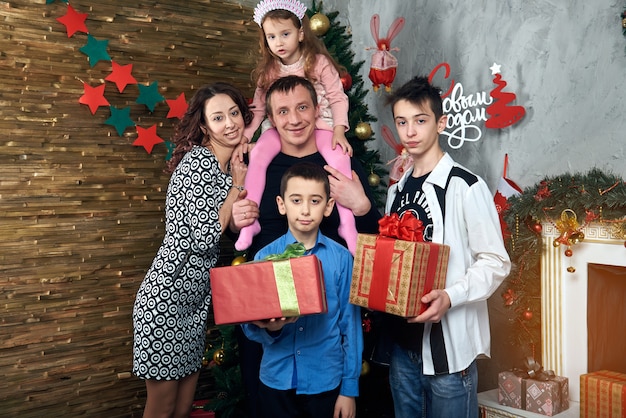 Famille heureuse: maman, papa et trois enfants au coin du feu pour les vacances d'hiver. Veille de Noël et réveillon du nouvel an.