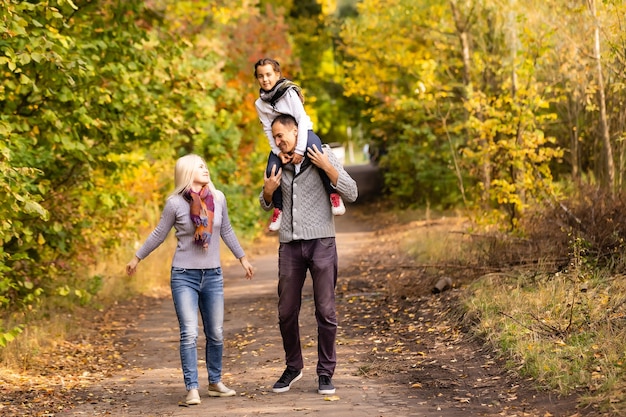 famille heureuse marchant dans le parc d'automne