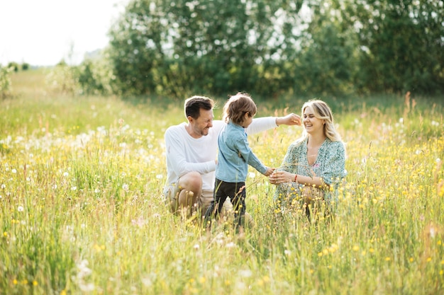 Famille heureuse marchant parmi la fleur dans le pré, heure d'été heureuse, photo