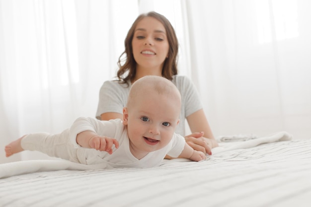 Photo famille heureuse. mère et bébé jouant et souriant sur le lit