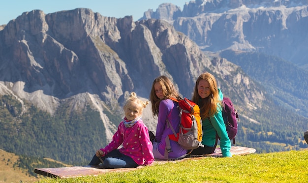 Famille heureuse - mère et deux sœurs filles randonneurs assis sur le banc dans les montagnes Dolomites, Italie. Seceda